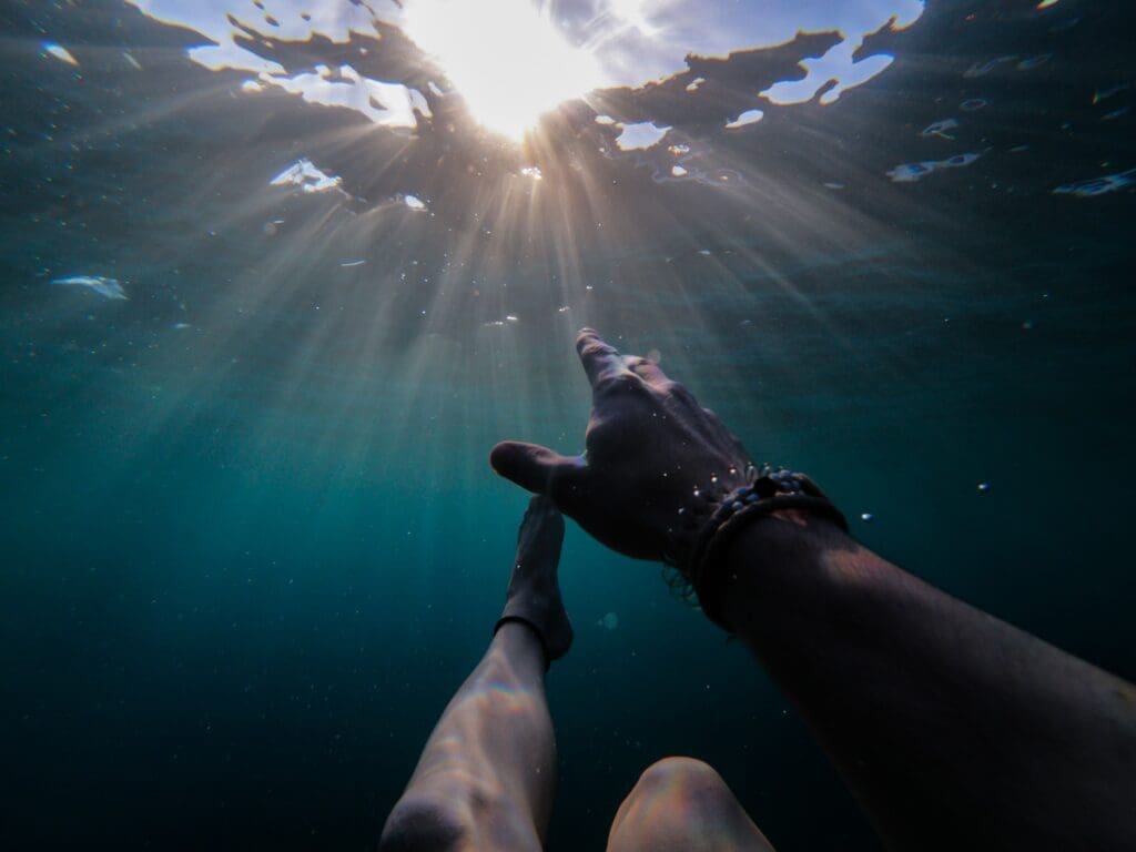 Photo of person under water reaching for the surface by Cristian Palmer for Unsplash