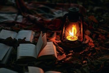 Photo of books in leaves with lantern by tengyart for unsplash